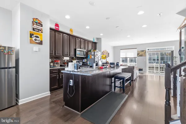 a kitchen with stainless steel appliances granite countertop a refrigerator a stove and a wooden floors