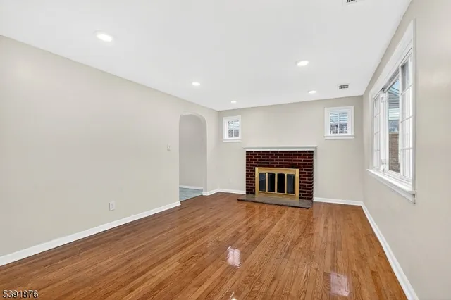 a view of empty room with wooden floor and fireplace