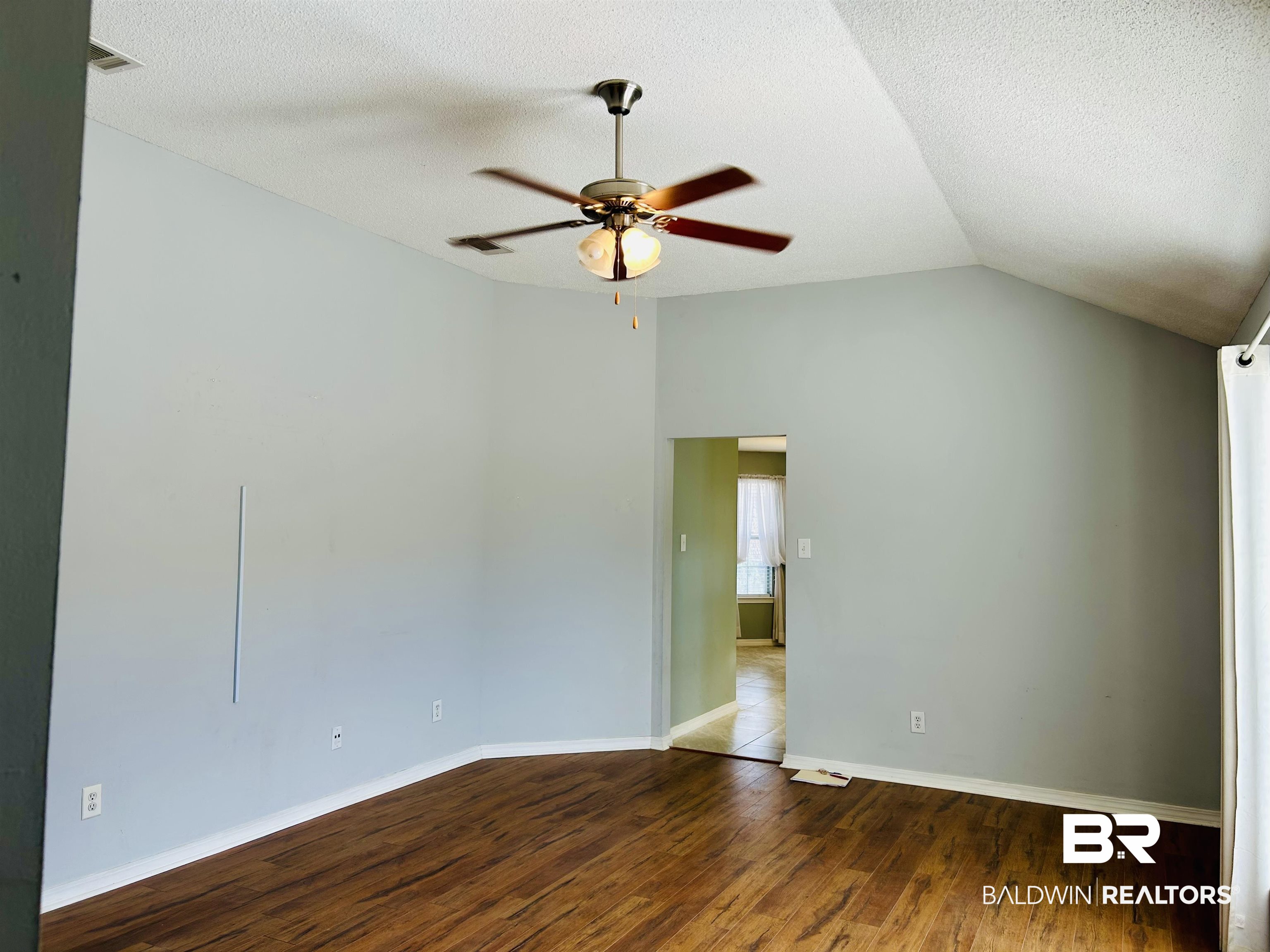 919 Parliament Court Mobile, AL 36695 - Photo 7 of 19 Spare room with hardwood / wood-style flooring, vaulted ceiling, a textured ceiling, and ceiling fan