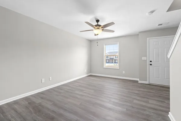 an empty room with wooden floor window and ceiling fan