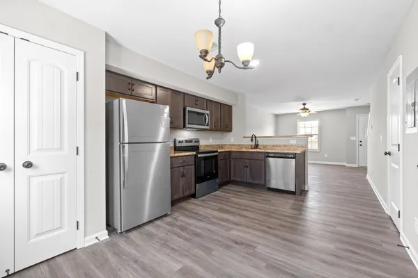 a kitchen with stainless steel appliances granite countertop a refrigerator a sink dishwasher a stove and a refrigerator