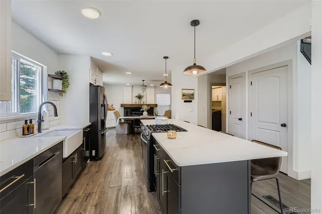 a large kitchen with kitchen island a stove a sink a refrigerator and a dining table with wooden floor