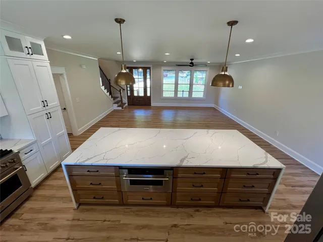 a kitchen with a stove chandelier and wooden floor