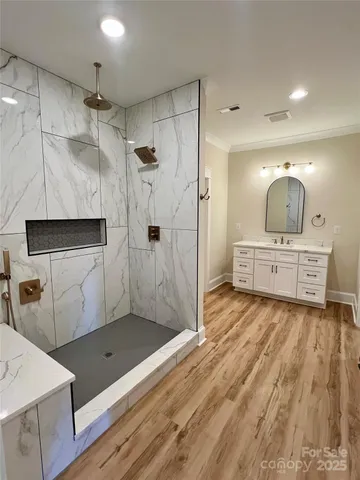 a view of an empty room with wooden floor and a bathroom