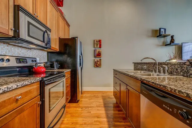 a kitchen with stainless steel appliances granite countertop a refrigerator and a stove top oven