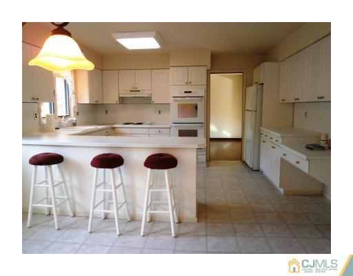 200 Old Forge Road Monroe Township, NJ 08831 - Photo 11 of 25 a kitchen with kitchen island a stove a chandelier and a refrigerator