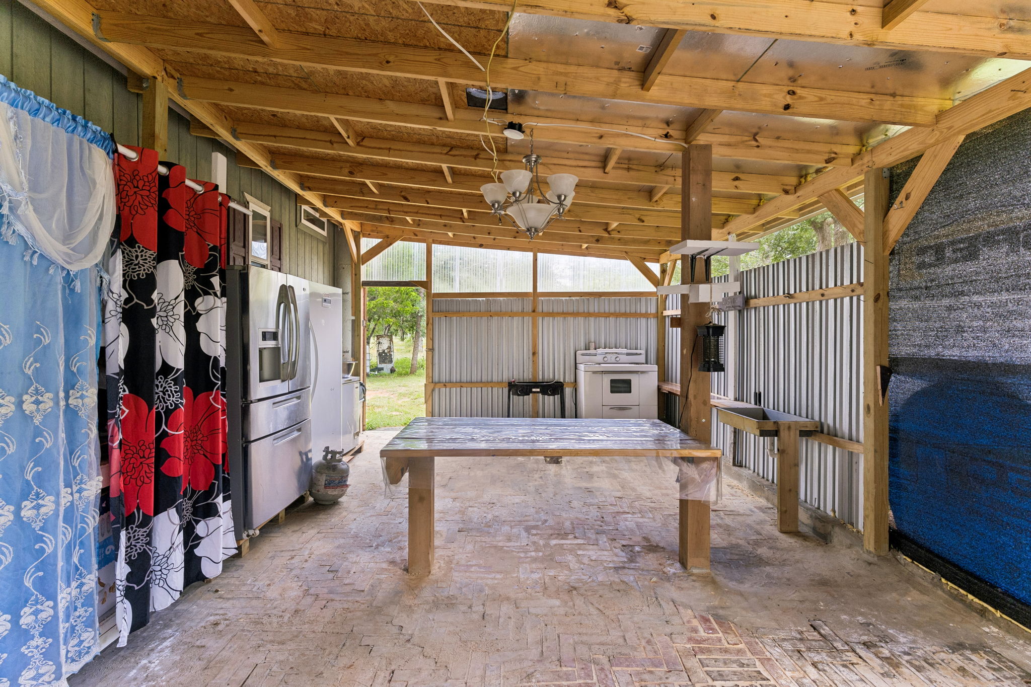253 North County Line Road, Unit C Elgin, TX 78621 - Photo 23 of 39 An inviting outdoor kitchen offers convenient appliances and rustic charm under a sturdy wooden canopy.