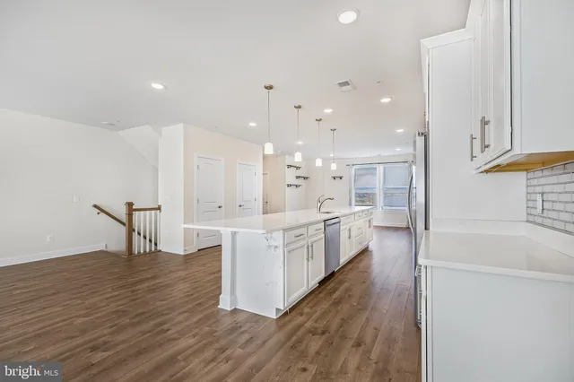a large white kitchen with wooden floor and a sink