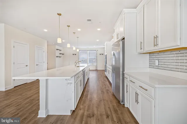 a kitchen with stainless steel appliances sink refrigerator and wooden floor