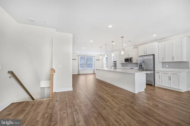 a large kitchen with white cabinets wooden floor and a sink