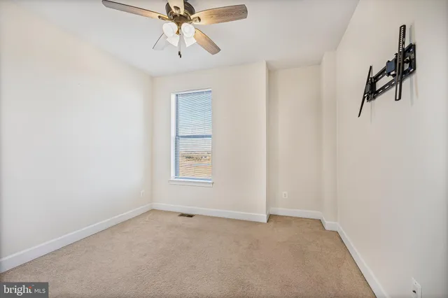 an empty room with a window and a ceiling fan