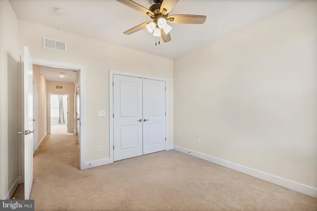 an empty room with a chandelier fan and closet