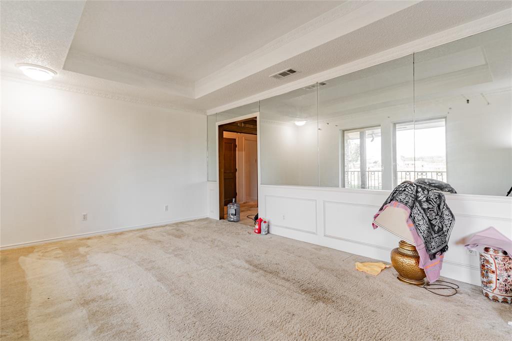 4320 Hickox Road Rowlett, TX 75089 - Photo 14 of 37 Recessed ceiling with crown molding, wall-mounted mirror panels, and white wainscoting