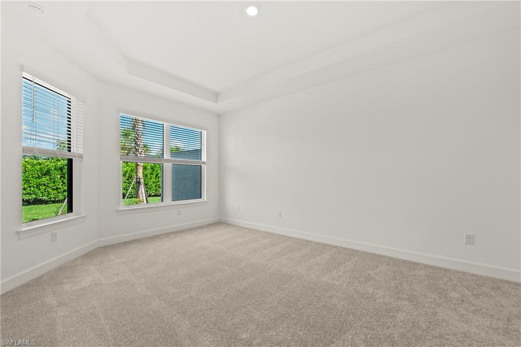15517 Vittorio Street Naples, FL 34114 - Photo 11 of 35 Spare room featuring carpet, baseboards, and a tray ceiling