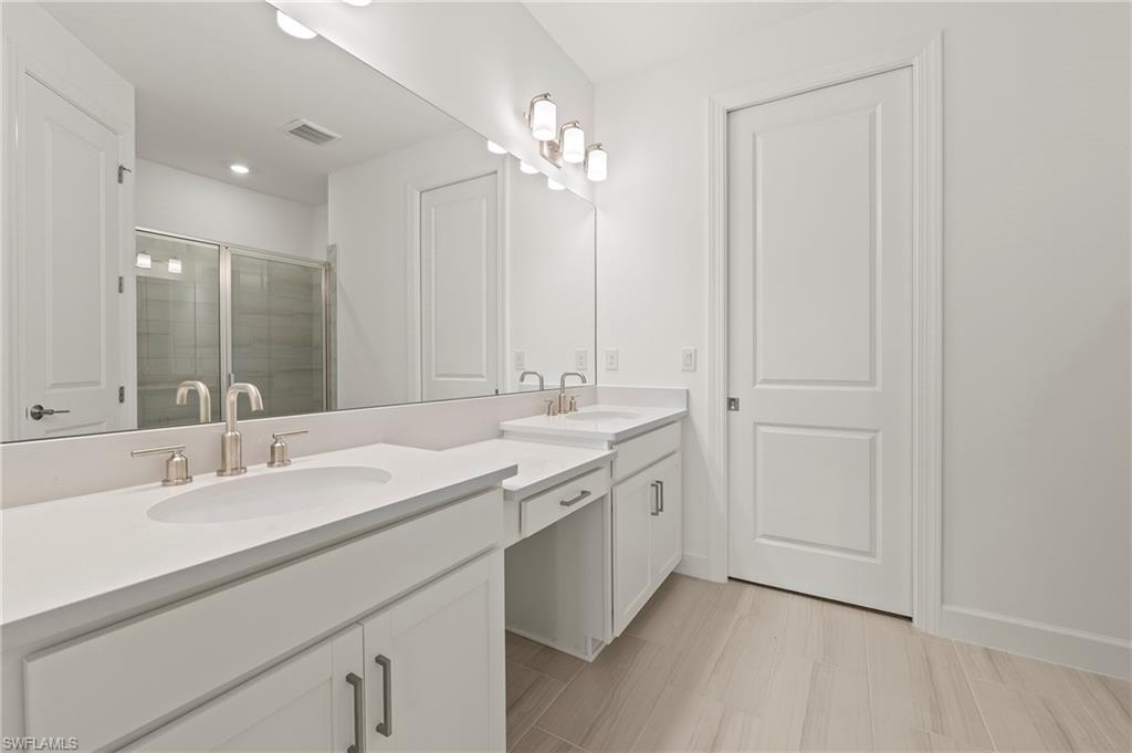 15517 Vittorio Street Naples, FL 34114 - Photo 12 of 35 Full bath with double vanity, a shower stall, and baseboards
