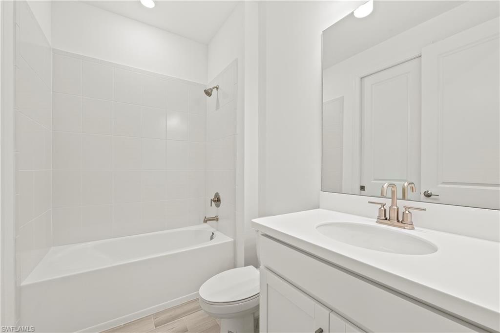 15517 Vittorio Street Naples, FL 34114 - Photo 16 of 35 Bathroom with vanity, toilet, wood finished floors, and tub / shower combination