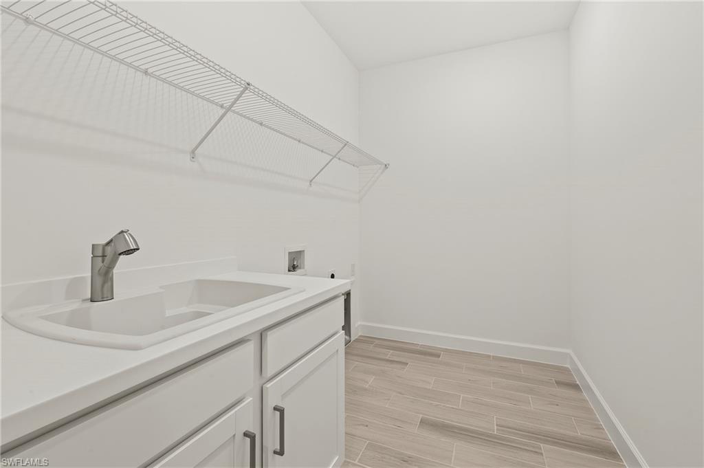 15517 Vittorio Street Naples, FL 34114 - Photo 17 of 35 Laundry room featuring baseboards, cabinet space, hookup for a washing machine, and wood finish floors