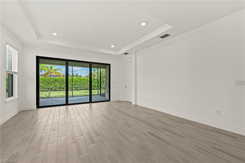 15517 Vittorio Street Naples, FL 34114 - Photo 20 of 35 Spare room featuring a tray ceiling, light wood-style flooring, baseboards, and recessed lighting