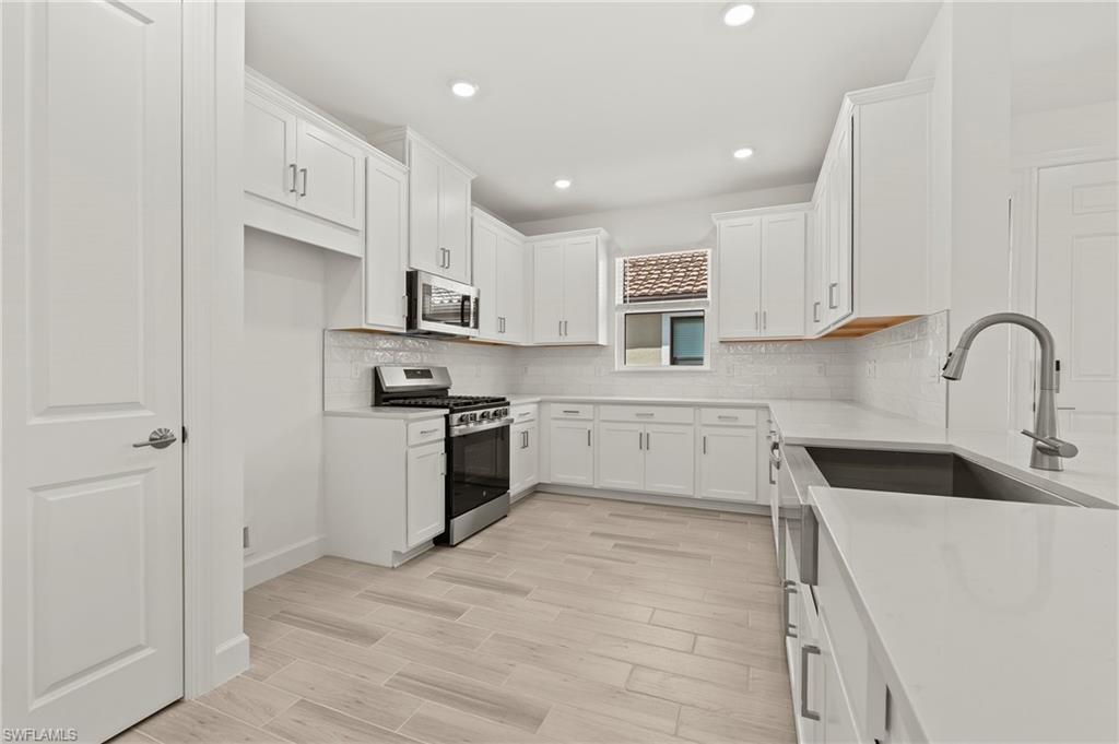 15517 Vittorio Street Naples, FL 34114 - Photo 21 of 35 Kitchen with stainless steel appliances, light wood-type flooring, white cabinetry, tasteful backsplash, and recessed lighting