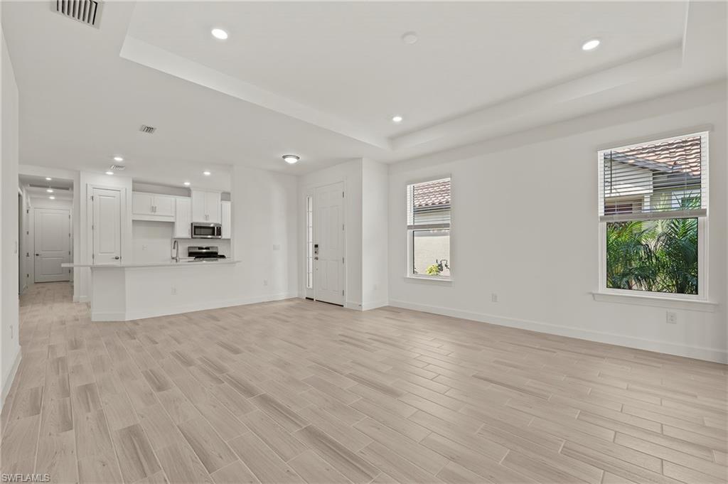 15517 Vittorio Street Naples, FL 34114 - Photo 4 of 35 Unfurnished living room with a raised ceiling, baseboards, recessed lighting, and light wood finished floors
