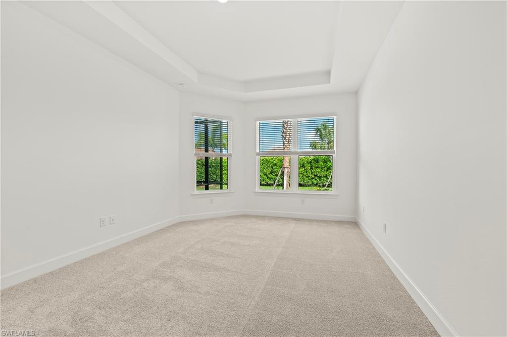 15517 Vittorio Street Naples, FL 34114 - Photo 10 of 35 Spare room featuring light carpet, baseboards, and a tray ceiling