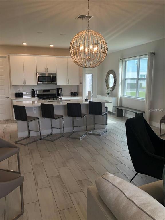 820 Driving Range Court Reunion, FL 34747 - Photo 15 of 45 a living room with couches kitchen view and a chandelier