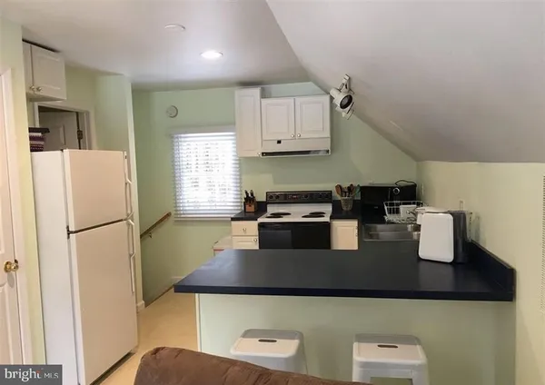 a kitchen with stainless steel appliances granite countertop a stove a refrigerator a sink a stove and white cabinets
