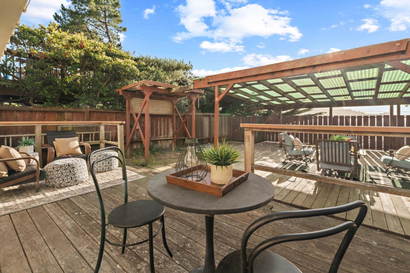 1212 Seville Drive Pacifica, CA 94044 - Photo 26 of 37 a view of a patio with a dining table and chairs with wooden floor and fence
