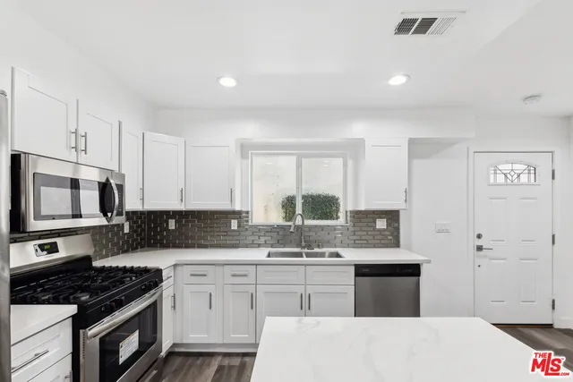 a kitchen with granite countertop a sink a stove and cabinets