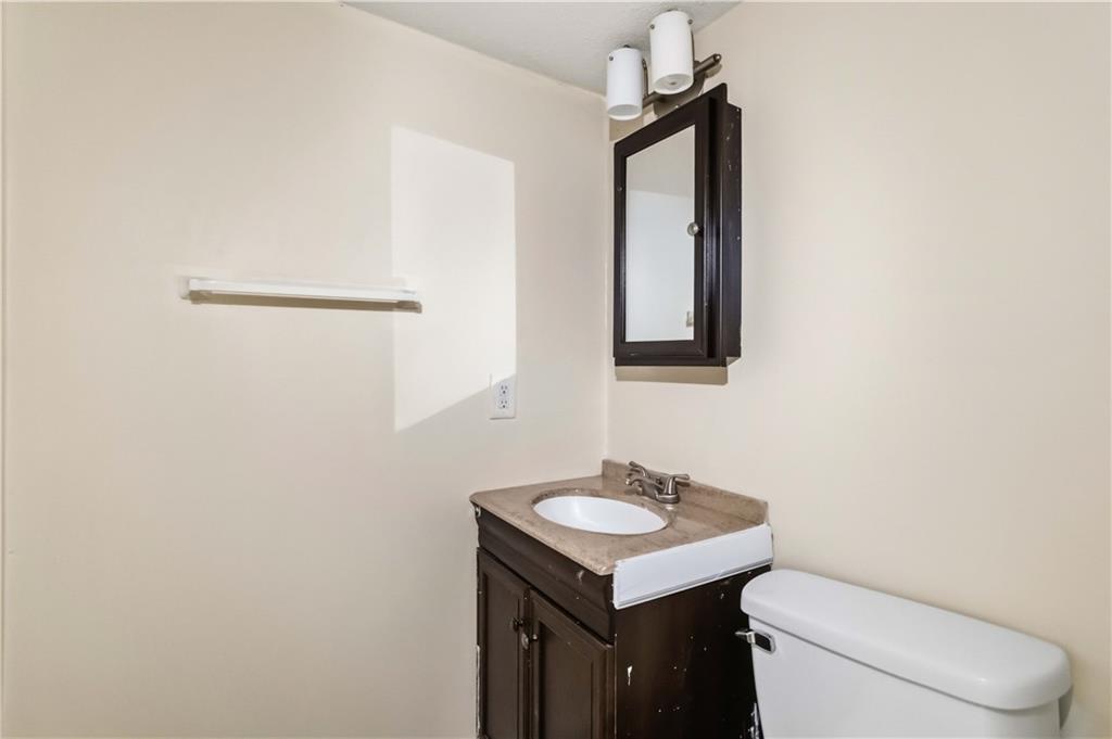 119 Plantation Circle Clarkston, GA 30021 - Photo 13 of 25 a bathroom with a toilet a sink a mirror and vanity