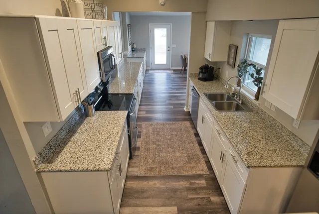 a kitchen with stainless steel appliances granite countertop a sink and a refrigerator