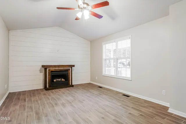 an empty room with windows and fireplace