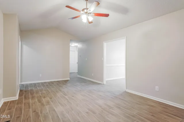 an empty room with wooden floor and fan