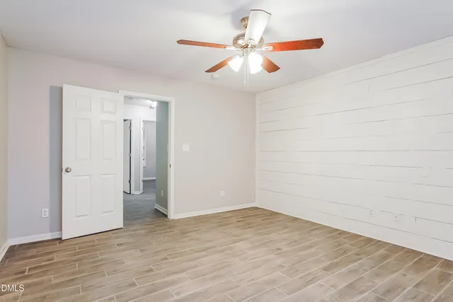 an empty room with wooden floor and ceiling fan