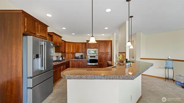 a kitchen with stainless steel appliances granite countertop a refrigerator a oven and a sink