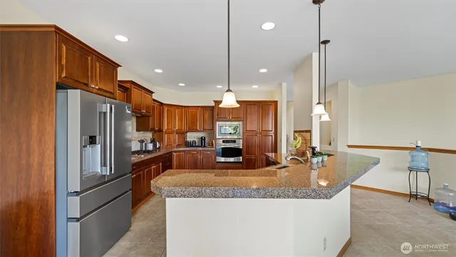 a kitchen with stainless steel appliances granite countertop a refrigerator a oven and a sink