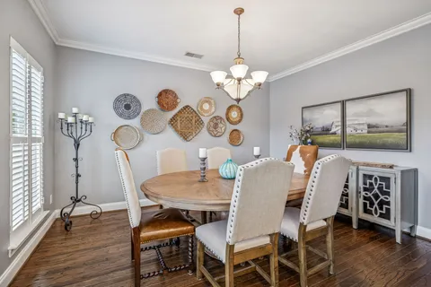 a view of a dining room with furniture a chandelier and wooden floor