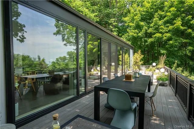 a view of a patio with table and chairs and floor to ceiling window with garden