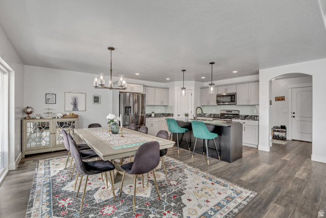 1577 Quailhill Road Saratoga Springs, UT 84045 - Photo 12 of 46 Dining room featuring arched walkways, dark wood-style floors, and a chandelier