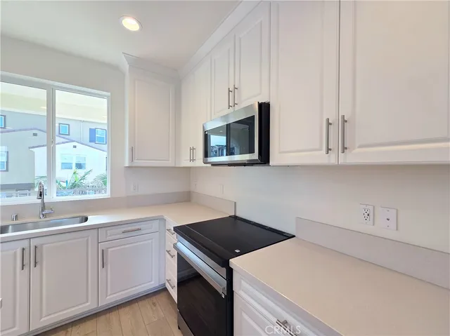 a kitchen with granite countertop white cabinets sink and stainless steel appliances