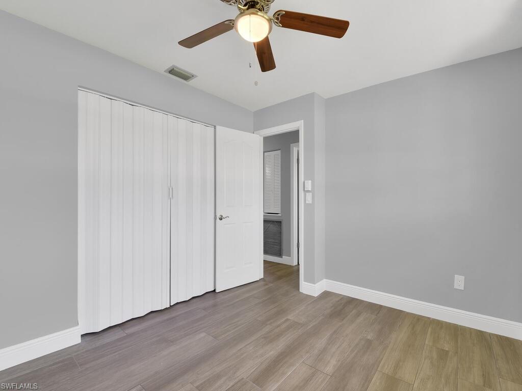 1958 41st Terrace Southwest Naples, FL 34116 - Photo 22 of 28 an empty room with wooden floor chandelier fan and closet area