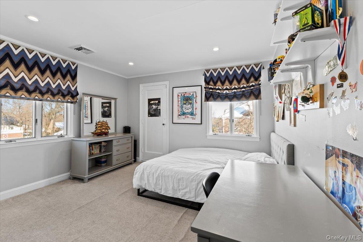 25 Pond Park Road Great Neck, NY 11023 - Photo 29 of 45 a spacious bedroom with a bed a dresser and windows