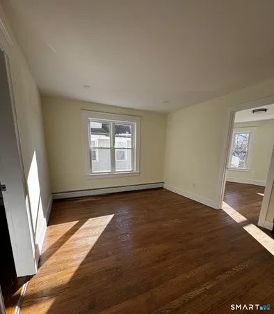 a view of an empty room with wooden floor and a window