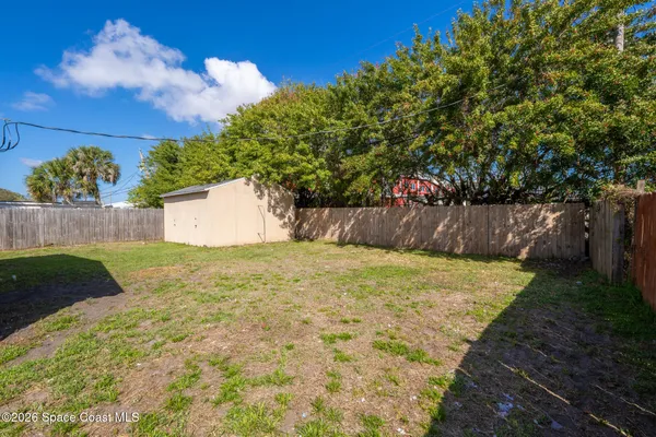 a view of small yard with large tree and wooden fence