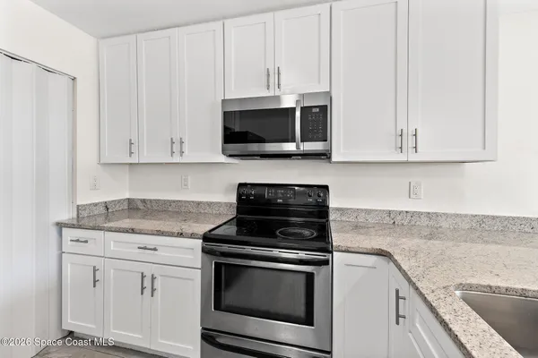 a kitchen with granite countertop white cabinets and a stove a oven with white countertops