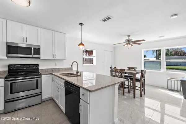 a kitchen with granite countertop stainless steel appliances a stove a sink a microwave a dining table and chairs