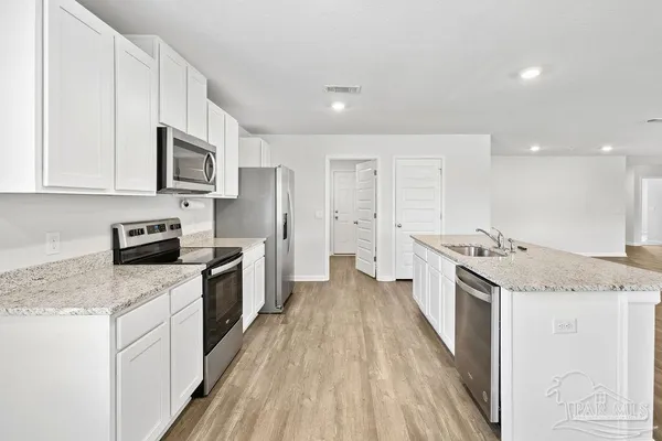 a large kitchen with a stove top oven a sink a counter space and cabinets