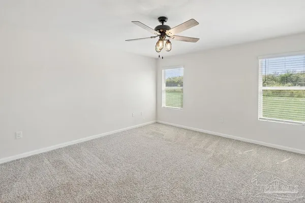 an empty room with windows and chandelier fan