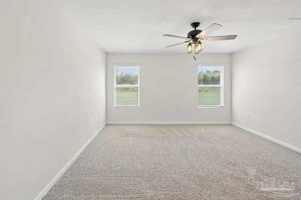 an empty room with windows and fan