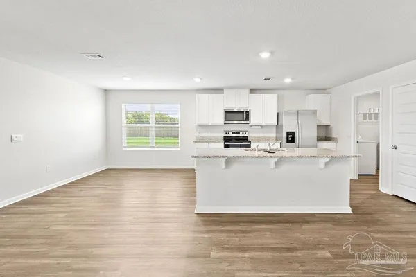 a view of a kitchen with kitchen island a sink wooden floor and a window